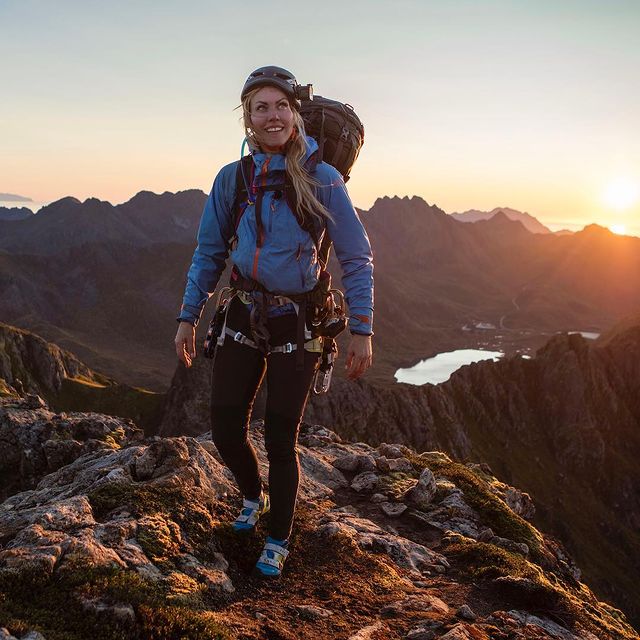 Silje Torp Færavaag climbing rock wearing a blue jacket carrying a bag